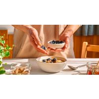 Person preparing a healthy bowl of fruit and whole grains